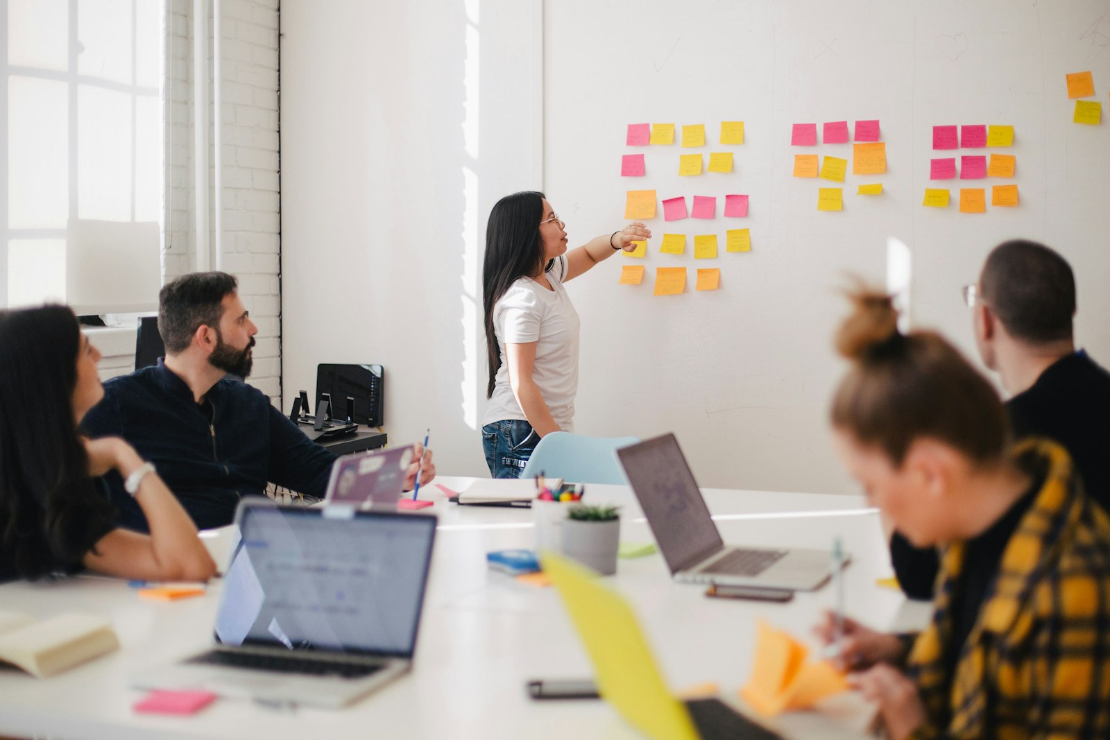 Manager presenting goals on a sticky-note wall to her team