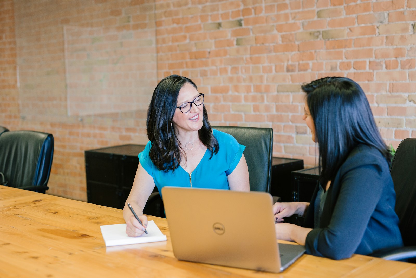 Two women talking across a table with a laptop during a meeting