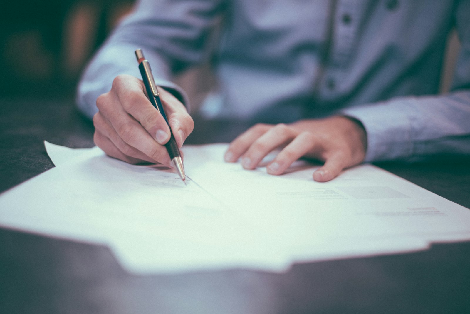 Hand signing official paperwork with a pen