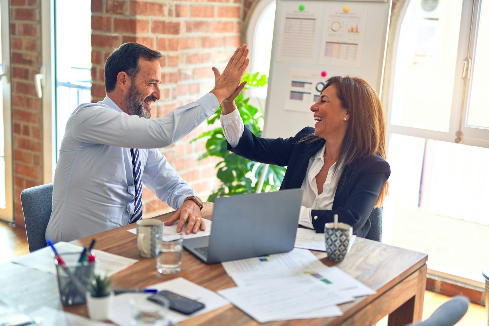 Business partners high-fiving across a meeting table